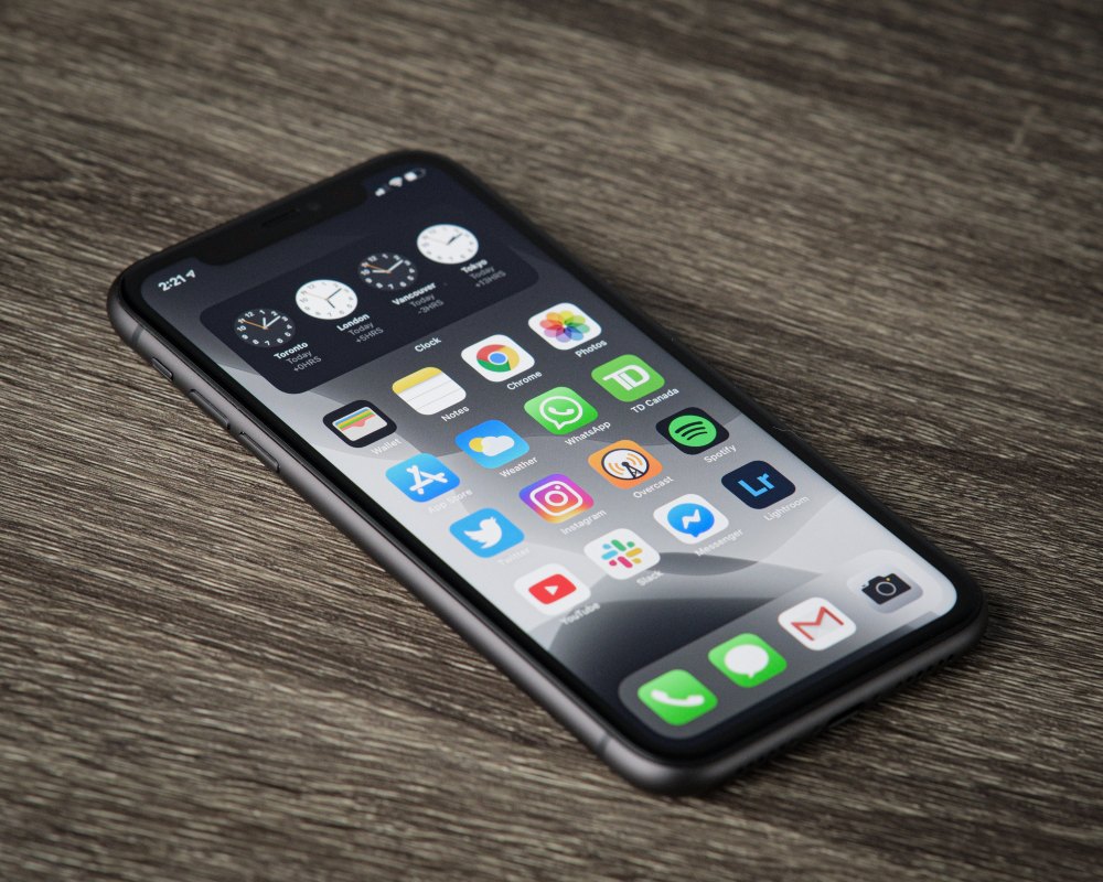 thom-bradley-A6qNzfJXRGQ-unsplash (1) Unlocked iPhone laying on a wooden table